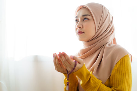 Beautiful Asian young Muslim woman sit on the floor in her house and praying for a holy god - Allah in Islam believe.の写真素材