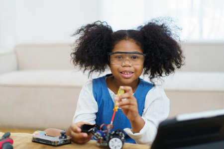 Happy cheerful American - African ethnicity girl enjoy learning to assemble a robot by herself. Creativity and thinkiing learning skill in elementary children.の写真素材