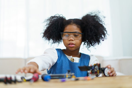 Happy cheerful American - African ethnicity girl enjoy learning to assemble a robot by herself. Creativity and thinkiing learning skill in elementary children.の写真素材