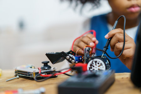 Happy cheerful American - African ethnicity girl enjoy learning to assemble a robot by herself. Creativity and thinkiing learning skill in elementary children.の写真素材