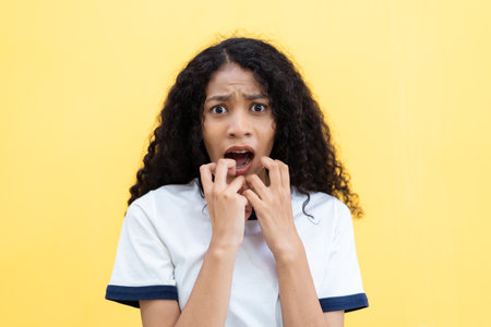 Portrait of beautiful American - African ethnicity black woman on yellow background with copyspace. Young black woman expressing or making her face scared - excited.の写真素材