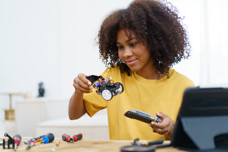 Happy cheerful American - African black ethnicity female university student learning about robotic and programing by herself, woman assemble a robot.の写真素材
