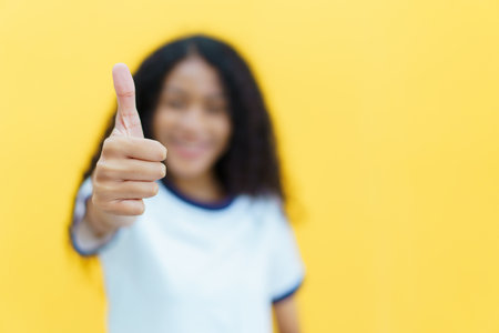 Confident happy black woman smiling to camera portrait on yellow background. Close up portrait of beautiful young black woman smiles and crossed arms.の写真素材