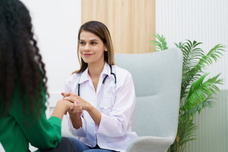 Female specialist or professional doctor giving a consulting to female patient in clinic. Doctor touching or holding on crisis patient's hand with empathy and care.の写真素材