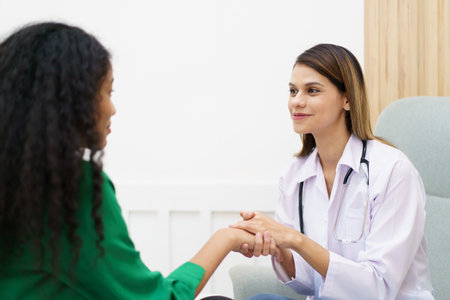 Female specialist or professional doctor giving a consulting to female patient in clinic. Doctor touching or holding on crisis patient's hand with empathy and care.の写真素材
