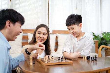 Happy Asian lovely family staying and playing a chess game together in living room in weekend, Group of Asian people playing chess game together in.の写真素材