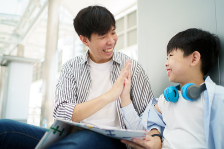 Happy cheerful Asian family traveling in the downtown together concept. Father looking at the railway station map with his son and pointing a forefinger on the map. Asian family tourist in city.の写真素材