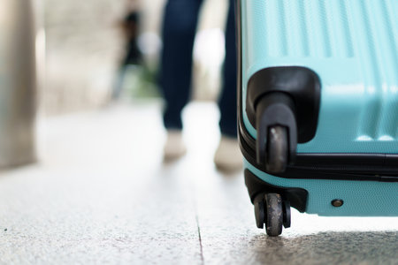 Asian young man dragging a suitcase along the city or airport terminal with shopping bags. Man traveling in the city or urban area.の写真素材