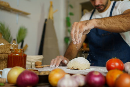 Happy cheerful Italian chef making a fresh pizza dough on wooden table in kitchen.の写真素材