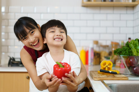 Happy cheerful mother and her little boy preparing a foods and vegetables in domestic kitchen together. Mother and son smiling and looking at the camera in kitchen.の写真素材