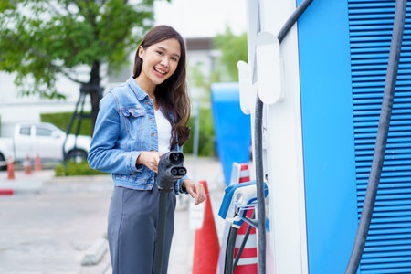 Unrecognizable Asian woman holding the CCS 2 EV charging connector at EV charging station, woman preparing an EV - electric vehicle charging connector for recharge a vehicle.の写真素材