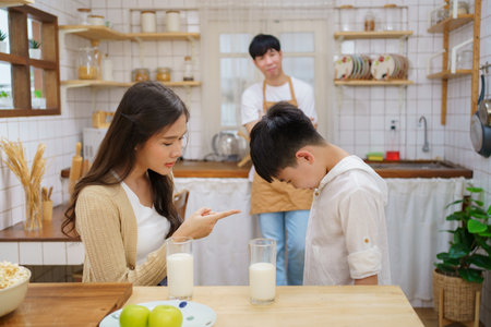 Mother yelling on her son in kitchen because his son deny to drink a milk and eat vegetables. Eating a healthy food problems in children.の写真素材
