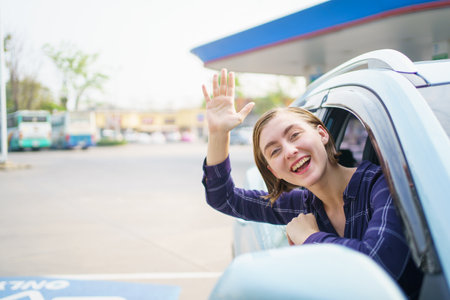 Happy cheerful caucasian white female car driver waving and smiling out of the car. Happy woman...