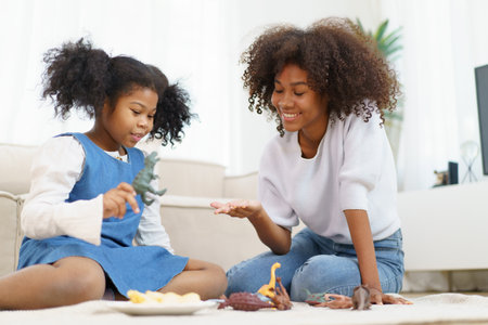 Happy cheerful American - African ethnic women lifestyle at home. Mother and daughter playing a dinosaur toys together in living room. Happy - relaxing family concept.の写真素材
