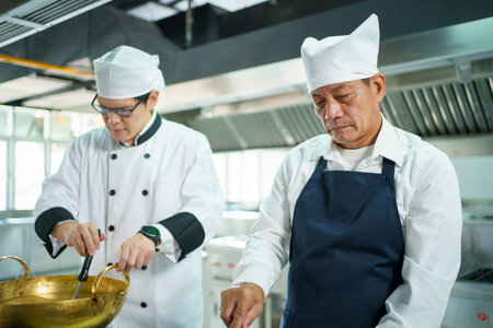 Happy Asian professional chef cooking in kitchen in Asian restaurant. Males professional chef cooking in Chinese kitchen.の写真素材