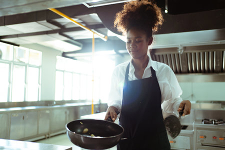 Happy African - black professional chef cooking in kitchen in restaurant.の写真素材