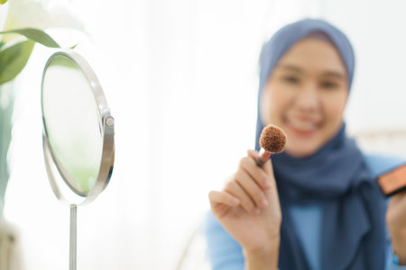 Modern lifestyles of female muslim people portrait, a beautiful Asian muslim woman applying a cosmetic and brushing her face. Modern muslim lifestyle concept.の写真素材