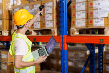 Professional warehouse staff using laptop computer - notebook to review the stock inventory on shelf in an import - export warehouse. Senior warehouse worker uses tablet to check an item on rack.の写真素材
