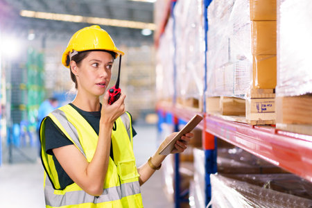 Happy cheerful caucasian white female warehouse worker talking to a team on walkie talkie. Professional occupation in logistic industrial concept.の写真素材