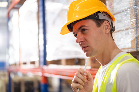 Professional warehouse staff using digital tablet to review the stock inventory on shelf in an import - export warehouse. Senior warehouse worker uses tablet to check an item on rack.の写真素材