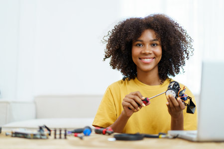 Happy cheerful American - African black ethnicity female university student learning about robotic and programing by herself, woman assemble a robot.の写真素材