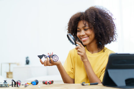 Happy cheerful American - African black ethnicity female university student learning about robotic and programing by herself, woman assemble a robot.の写真素材