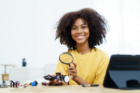 Happy cheerful American - African black ethnicity female university student learning about robotic and programing by herself, woman assemble a robot.の写真素材