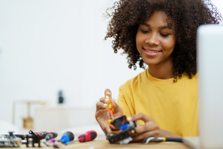Happy cheerful American - African black ethnicity female university student learning about robotic and programing by herself, woman assemble a robot.の写真素材