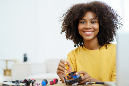 Happy cheerful American - African black ethnicity female university student learning about robotic and programing by herself, woman assemble a robot.の写真素材