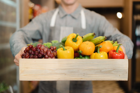 Happy cheerful caucasian grocery store staff arranging a vegetables and fruits on the shelf. Woman staff are working in food and vegetable hypermarket or grocery store.の写真素材