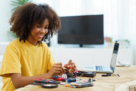 Happy cheerful American - African black ethnicity female university student learning about robotic and programing by herself, woman assemble a robot.の写真素材