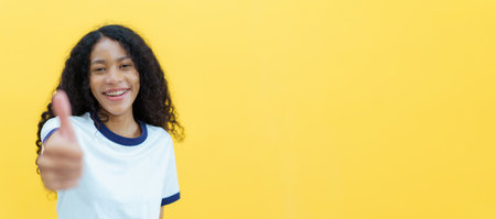 Confident happy black woman smiling to camera portrait on yellow background. Close up portrait of beautiful young black woman smiles and crossed arms.の写真素材