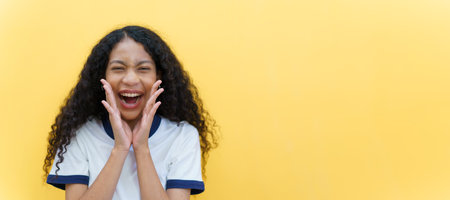 Cheerful black - American African woman yelling with hands close up on yellow background. Happy beautiful girl using hands at mount while screaming, woman speaking louder. Advertising concept.の写真素材