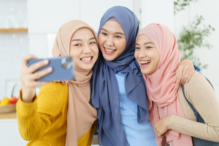 Group of happy cheerful Asian muslim women taking a selfie photography or making video live steaming on a social network by using smartphone.の写真素材