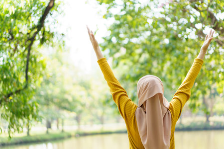 Happy cheerful Asian beautiful female muslim practicing an exercise and stretching at the park close up with copyspace. Modern muslim woman lifestyles and diversity concept.の写真素材