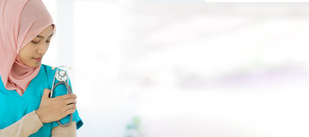 Asian female muslim doctor holding a doctor or medical stethoscope and crossed arms close up with copyspace. An expertise or occupation in modern muslim people concept.の写真素材