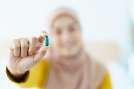 Asian young muslim woman showing a pill and water bottle, muslim woman taking a pill capsule. Health care and wellness in diverse ethnicity people and religious concept.の写真素材
