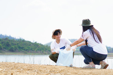 Group of Asian young people volunteer helping to collecting or picking up a plastic bottle garbage on the ground in park. Sustainability and environment conservation concept.の写真素材