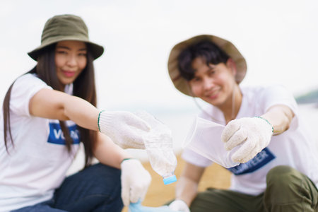Group of Asian young people volunteer helping to collecting or picking up a plastic bottle garbage on the ground in park. Sustainability and environment conservation concept.の写真素材