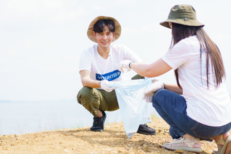Group of Asian young people volunteer helping to collecting or picking up a plastic bottle garbage on the ground in park. Sustainability and environment conservation concept.の写真素材