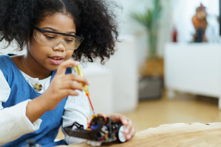 Happy cheerful American - African ethnicity girl enjoy learning to assemble a robot by herself. Creativity and thinkiing learning skill in elementary children.の写真素材