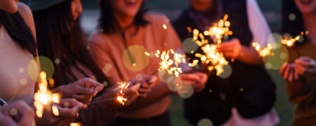 Group of Asian young men and women celebrating together with a sparkling firework in the evening. Happy men and women enjoy playing a sparklers firework in a party.の写真素材