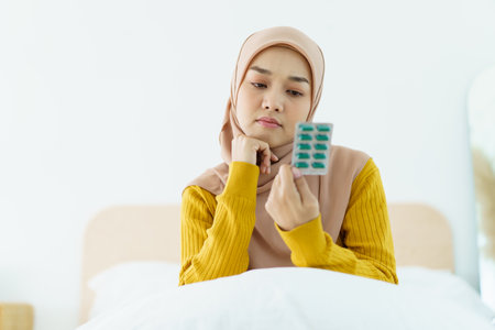 Asian young muslim woman showing a pill and water bottle, muslim woman taking a pill capsule. Health care and wellness in diverse ethnicity people and religious concept.の写真素材