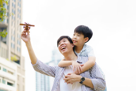 Happy cheerful Asian daddy and little son playing with a wooden air plane toy together, a concept of creativity - education in children learning.の写真素材