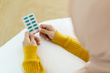 Asian young muslim woman showing a pill and water bottle, muslim woman taking a pill capsule. Health care and wellness in diverse ethnicity people and religious concept.の写真素材