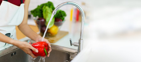 Happy healthy Asian woman washing a vegetables in domestic kitchen faucet before cooking. A housewife preparing and cleaning a fruits and vegetables carefully for cooking a healthy meal.の写真素材