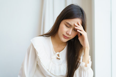 Unhappy - stressful Asian young woman having a depression disease, woman got a headache and touching on her head.の写真素材