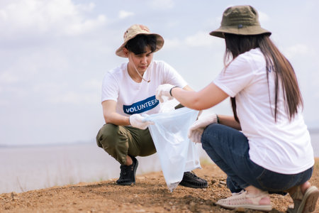 Group of Asian young people volunteer helping to collecting or picking up a plastic bottle garbage on the ground in park. Sustainability and environment conservation concept.の写真素材