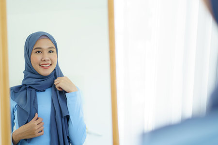Modern lifestyles of female muslim people portrait, a beautiful Asian muslim woman applying a cosmetic and brushing her face. Modern muslim lifestyle concept.の写真素材