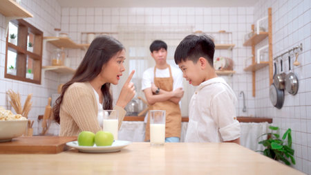 Mother yelling on her son in kitchen because his son deny to drink a milk and eat vegetables. Eating a healthy food problems in children.の写真素材